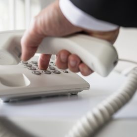 Businessman dialing a telephone number in order to make a phone call.