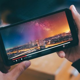 Online movie stream with smartphone. Young man  watching film on mobile phone with imaginary video player service.