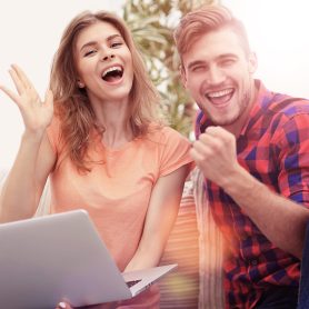happy couple rejoices,sitting on the couch in front of the open laptop